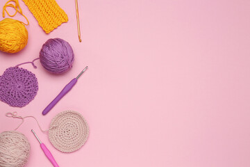 Flat lay composition with knitting threads and crochet hooks on pink background, space for text