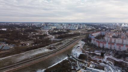 Construction site in a city vacant lot. Close to populated urban areas. Traces of heavy construction equipment are visible on the ground. Snow covered earth. Aerial photography.