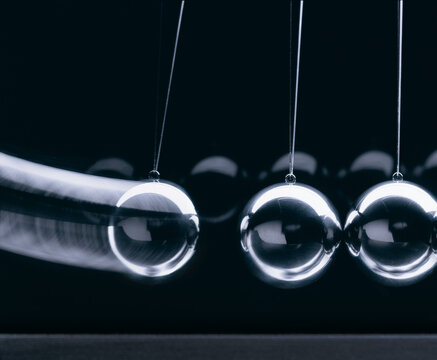 nahaufnahme von 3 kugeln eines newton-pendels in Aktion vor dunklem hintergrund