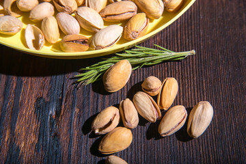 Pistachio nuts in a yellow bowl on a wooden background, side view, copy space