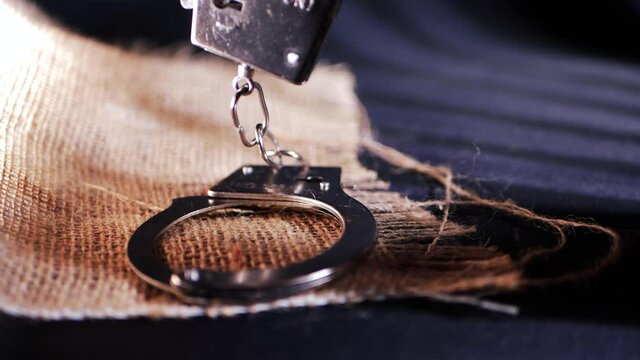 Handcuffs in prison shadows on sackcloth background