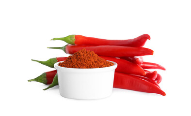 Fresh chili peppers and bowl of paprika powder on white background