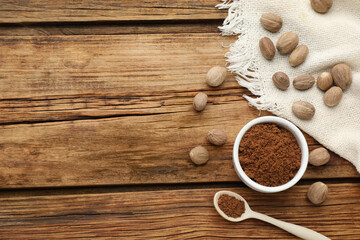 Ground nutmeg and whole seeds on wooden table, flat lay. Space for text