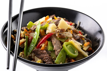 Beef, vegetables and sesame seeds in black bowl isolated on white background. 	