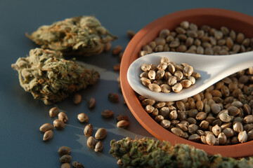 A bunch of cannabis seeds lie on a spoon and plate with several dried buds