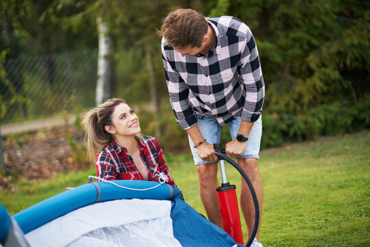 Young nice couple having fun on camping setting up tent
