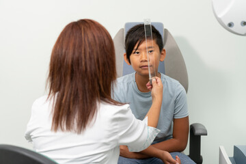 Asian boy in a consultation of an ophthalmologist woman with a prism