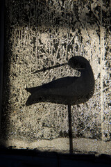 frosty winter window with wooden bird silhouette - 480927196