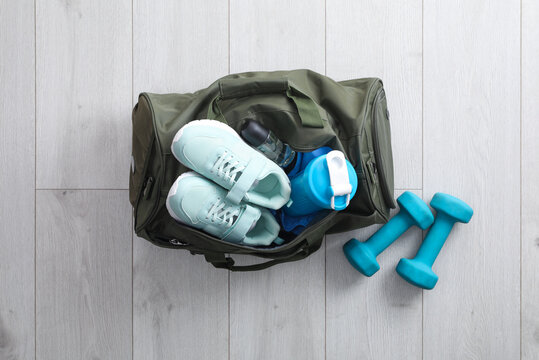 Sports bag with gym stuff and equipment on white floor, flat lay