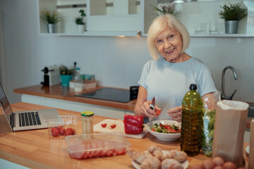 Aged woman chopping vegetables at home kitchen