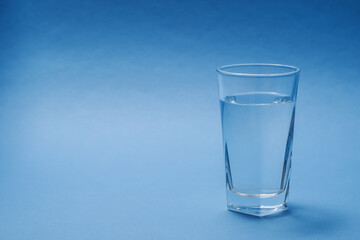 Glass with fresh water on a blue background.