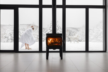 Woman enjoys winter time playing with dogs near house with cozy burning fireplace. Concept of...