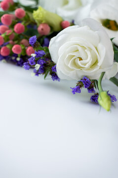 Blurred image of white eustoma and lilac limonium and pink berries on a white background with space for writing text.