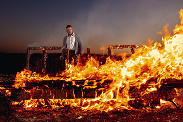 Young guy in the evening. in the foreground. The man is behind the fire