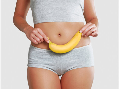 Fitness young woman holding a banana leaning on her belly.