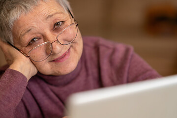 A senior woman sitting in front of a laptop communicates online through social networks.