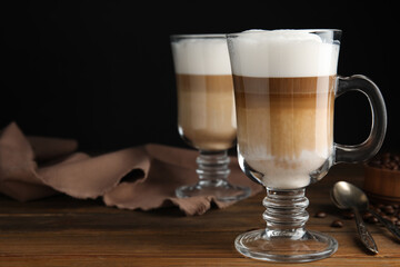 Delicious latte macchiato and coffee beans on wooden table, space for text