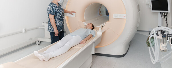 Doctor or nurse and patient with tomography CT or MRI Scan in hospital. Interior of radiography department. Technologically advanced equipment in white room. Magnetic resonance diagnostics machine