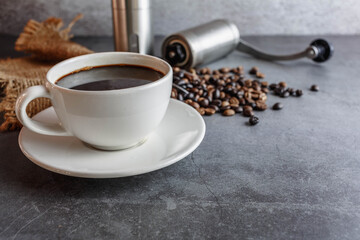 Hand coffee grinder and coffee beans and coffee cup on table.