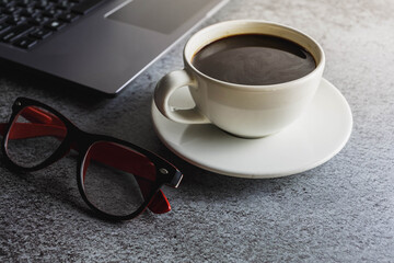 Coffee cup on desk with laptop and glasses