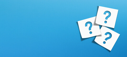 Note paper with question marks on panoramic blue background	