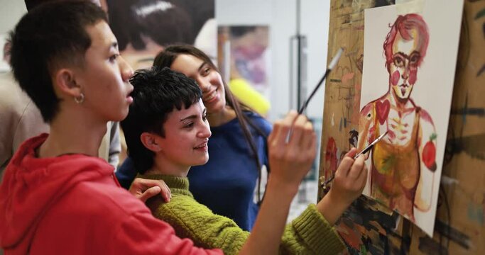 Multiracial students painting together inside art classroom at college university