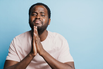 Black bristle man crying while holding his palms together