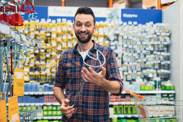 satisfied customer in a hardware store with a mixer attachment in his hands.