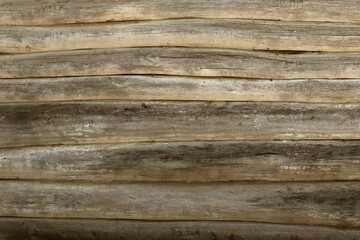 The wall of an old wooden house made of darkened weathered logs. Texture of old vintage wooden planks background natural.
