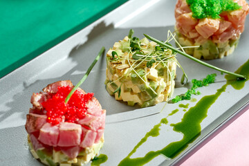 Tartar with tuna, avocado and white sauce in a gray plate. Colored backgrounds. Hard light. selective focus