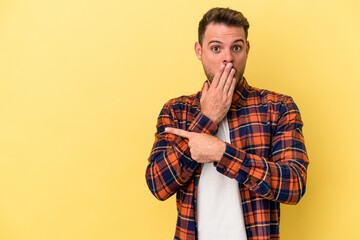 Young caucasian man isolated on yellow background pointing to the side