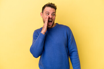 Young caucasian man isolated on yellow background shouting excited to front.