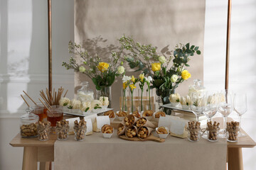 Delicious treats and glasses of drink on wooden table in room. Sweet buffet