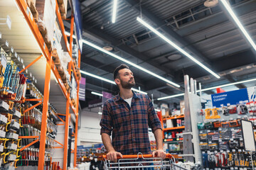buy a man walking with a basket in a hardware store - obrazy, fototapety, plakaty