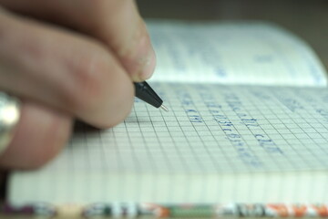 man's hand writes the text in a notebook 