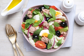 Bowl of delicious salad with canned tuna and vegetables served on white wooden table, flat lay