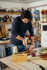 man preparing food in kitchen . he is cutting red onion