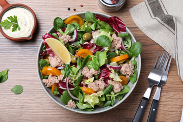 Bowl of delicious salad with canned tuna and vegetables served on wooden table, flat lay