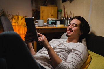 boy laying in his room eating junk food and using digital tablet