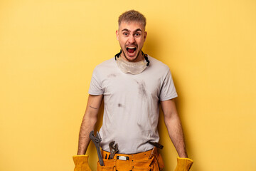 Young electrician caucasian man isolated on yellow background screaming very angry and aggressive.