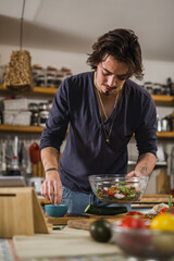 Fototapeta na wymiar man seasoning salad. preparing lunch in kitchen