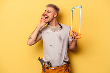 Young electrician caucasian man isolated on yellow background shouting and holding palm near opened mouth.