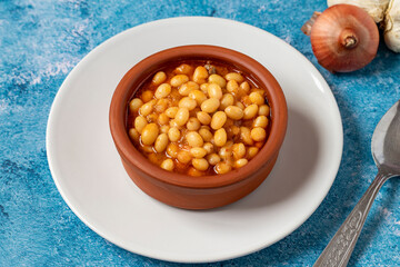 Hot turkish bean stew on blue background. Ispir beans cooked in a casserole - Kuru Fasulye