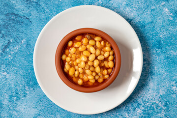 Hot turkish bean stew on blue background. Ispir beans cooked in a casserole - Kuru Fasulye
