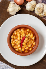 Hot turkish bean stew on wooden background. Ispir beans cooked in a casserole - Kuru Fasulye. Top view
