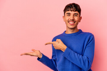 Young mixed race man isolated on pink background excited holding a copy space on palm.