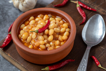 Hot turkish bean stew on wooden background. Ispir beans cooked in a casserole - Kuru Fasulye. Top view