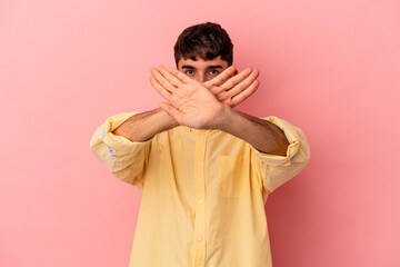 Young mixed race man isolated on pink background doing a denial gesture