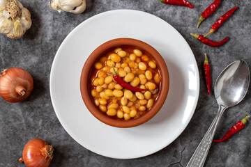 Hot turkish bean stew on dark background. Ispir beans cooked in a casserole - Kuru Fasulye. Top view