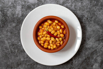 Hot turkish bean stew on dark background. Ispir beans cooked in a casserole - Kuru Fasulye. Top view
